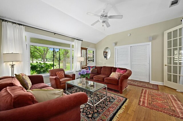 living area featuring a ceiling fan, visible vents, wood finished floors, and vaulted ceiling