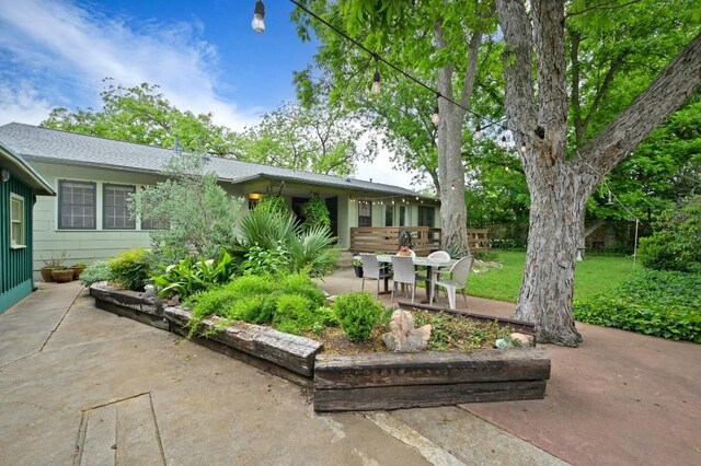 rear view of house featuring a patio, roof with shingles, and a yard