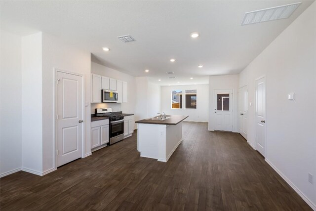 kitchen with white cabinets, dark countertops, appliances with stainless steel finishes, visible vents, and dark wood-style floors