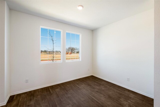 unfurnished room featuring baseboards and dark wood finished floors