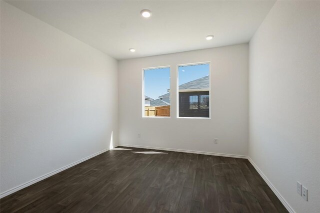 spare room with baseboards, recessed lighting, and dark wood-style flooring