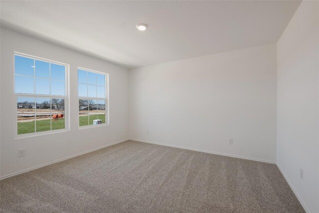 carpeted spare room featuring baseboards