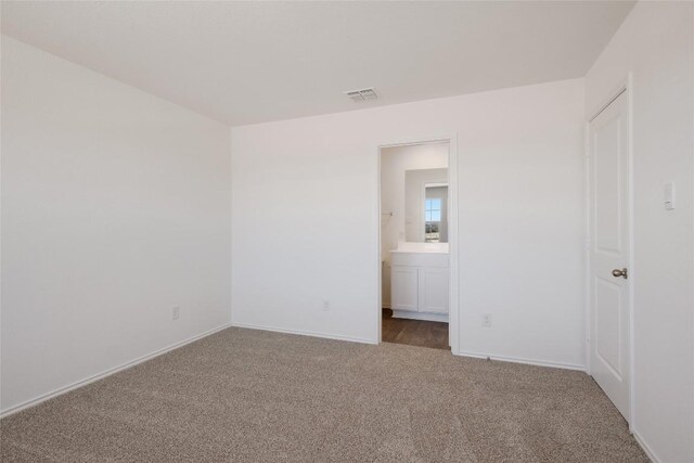 interior space with baseboards, carpet, ensuite bath, and visible vents