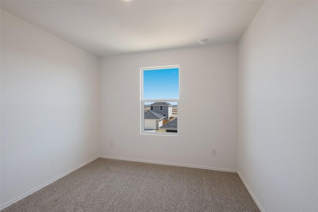 carpeted spare room featuring baseboards