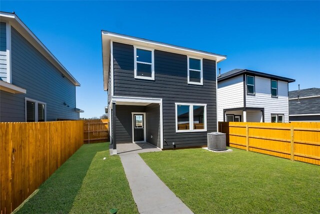 rear view of house with a fenced backyard, central air condition unit, and a yard