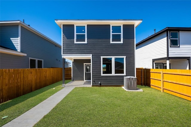 rear view of house with a fenced backyard, a lawn, and central AC