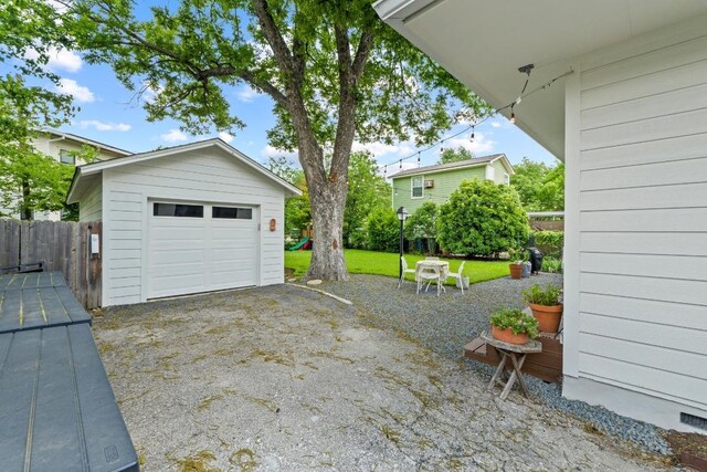 detached garage featuring fence and driveway