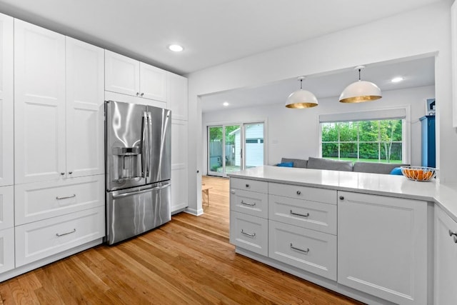 kitchen featuring stainless steel refrigerator with ice dispenser, a peninsula, light wood finished floors, recessed lighting, and white cabinetry
