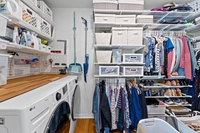 clothes washing area featuring washer and dryer, laundry area, baseboards, and wood finished floors