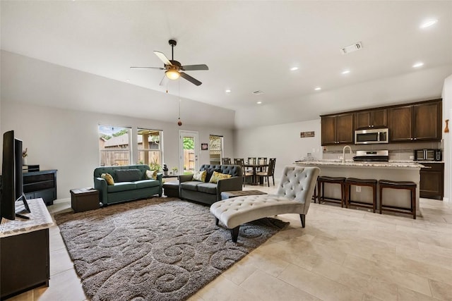 living room with ceiling fan, visible vents, vaulted ceiling, light tile patterned floors, and recessed lighting