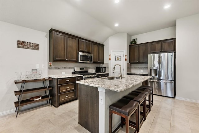 kitchen with stainless steel appliances, vaulted ceiling, a sink, and dark brown cabinets