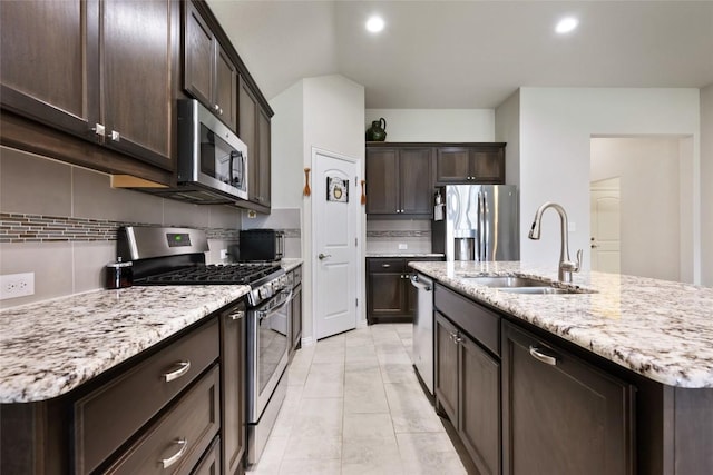 kitchen with backsplash, dark brown cabinets, appliances with stainless steel finishes, and a sink
