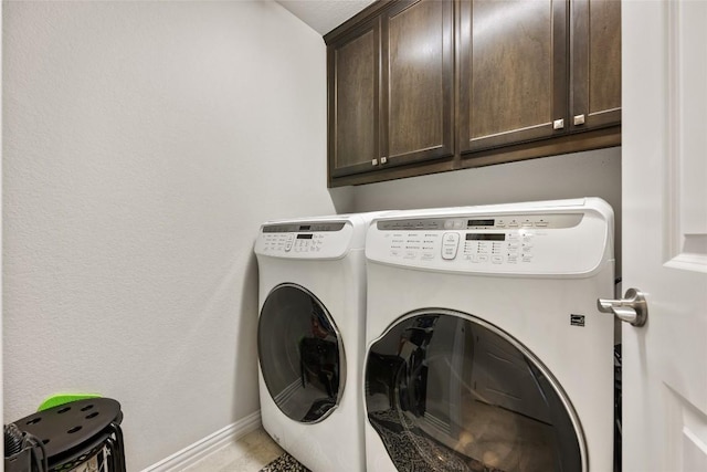 clothes washing area with cabinet space, baseboards, and washer and clothes dryer
