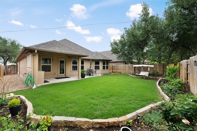 rear view of property with a lawn, a shingled roof, a patio area, and a fenced backyard