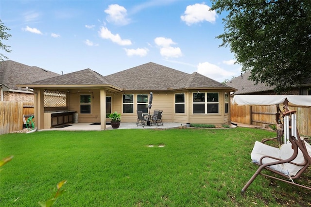rear view of house featuring roof with shingles, a hot tub, a fenced backyard, a lawn, and a patio