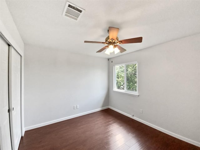 unfurnished bedroom featuring dark wood finished floors, a ceiling fan, baseboards, visible vents, and a closet