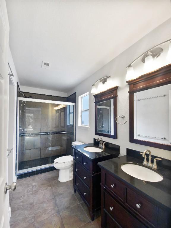 full bathroom with toilet, visible vents, a sink, and a stall shower