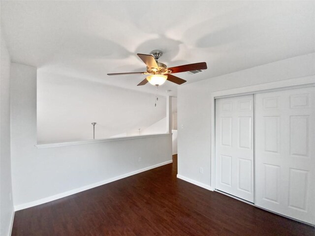 unfurnished bedroom with a ceiling fan, visible vents, wood finished floors, baseboards, and a closet