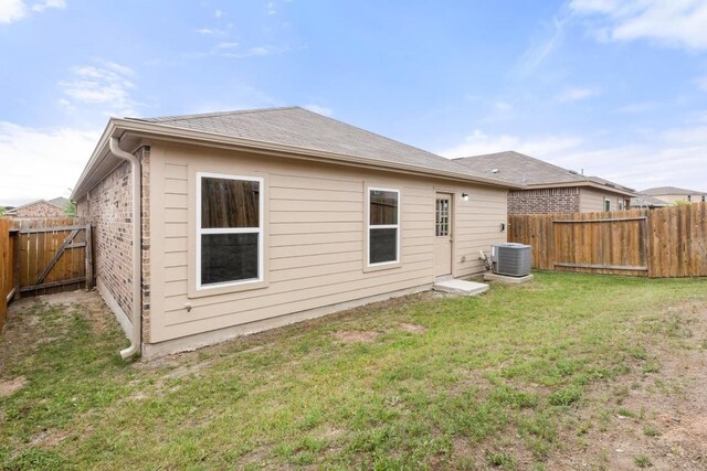 back of house featuring a yard, central AC, and a fenced backyard