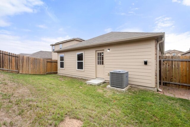 back of property with a yard, cooling unit, and a fenced backyard