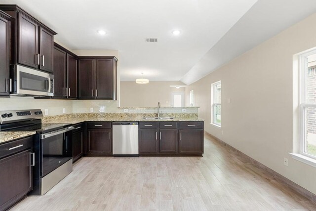 kitchen with dark brown cabinetry, appliances with stainless steel finishes, a sink, a peninsula, and visible vents