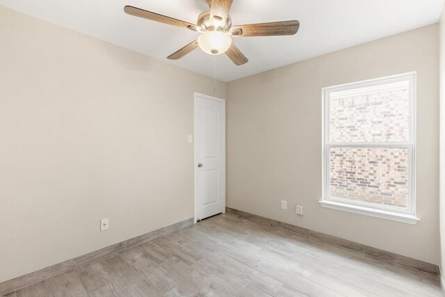 empty room with ceiling fan, plenty of natural light, baseboards, and light wood-style floors