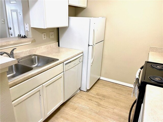 kitchen with white dishwasher, electric stove, light countertops, white cabinetry, and a sink