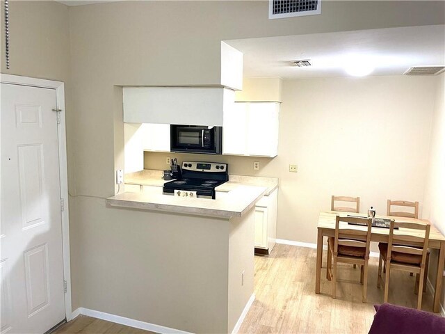 kitchen featuring visible vents, black microwave, stainless steel electric stove, and light wood-type flooring