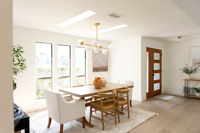dining area featuring an inviting chandelier, baseboards, light wood-style flooring, and visible vents