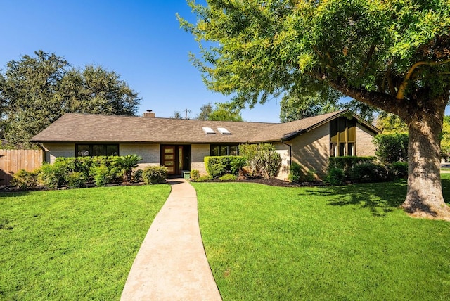 single story home featuring brick siding, a front lawn, fence, and a chimney