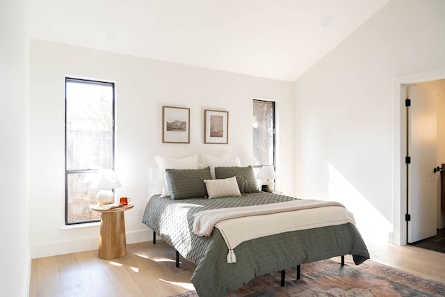 bedroom featuring baseboards, lofted ceiling, and wood finished floors