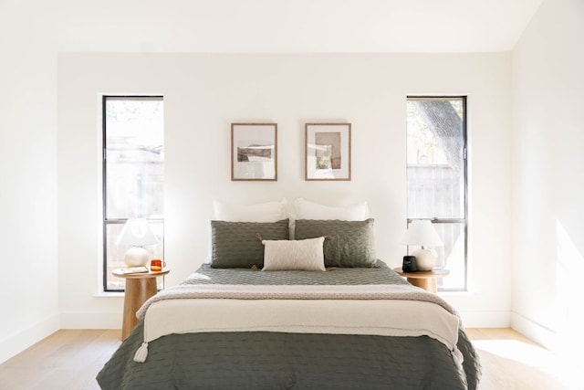 bedroom featuring baseboards, multiple windows, and light wood-style floors