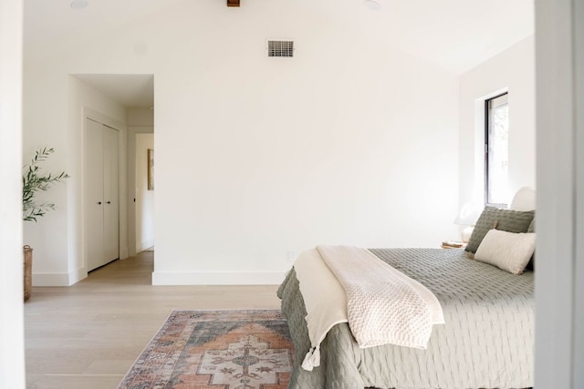 bedroom with visible vents, baseboards, lofted ceiling, and wood finished floors