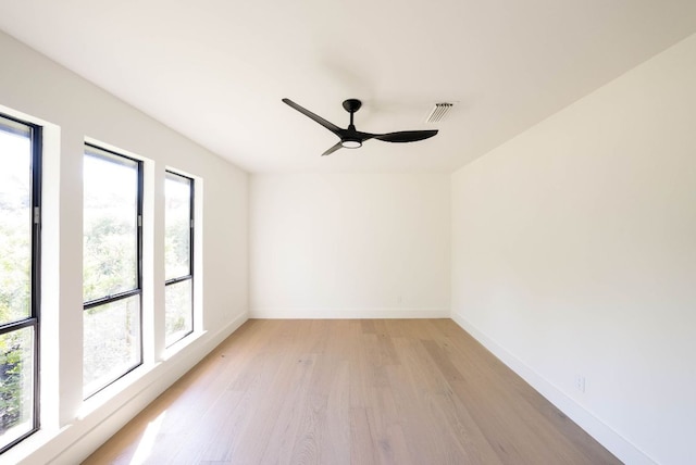 empty room with baseboards, ceiling fan, light wood-style flooring, and visible vents