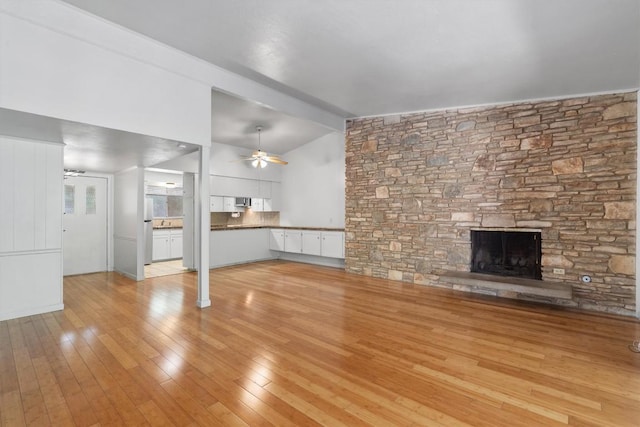 1304 Mariposa Dr Unit 231, Austin, TX 78704 - unfurnished living room featuring ceiling fan, lofted ceiling, a stone fireplace, and light wood-type flooring