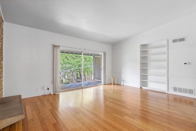 unfurnished living room with built in features, vaulted ceiling, wood finished floors, and visible vents