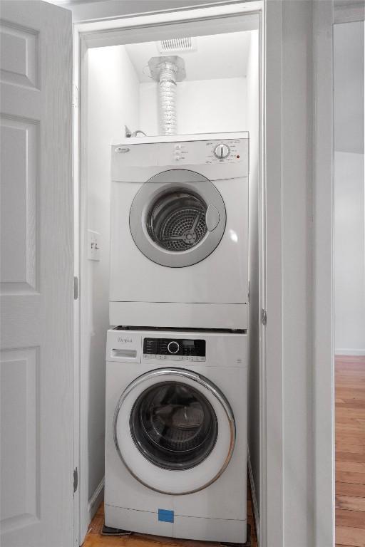 laundry area featuring stacked washer and dryer, laundry area, and light wood-style flooring