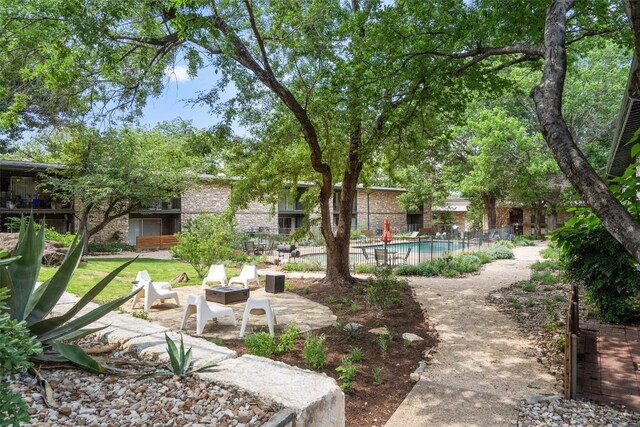 view of yard with fence, a patio, a community pool, and a fire pit