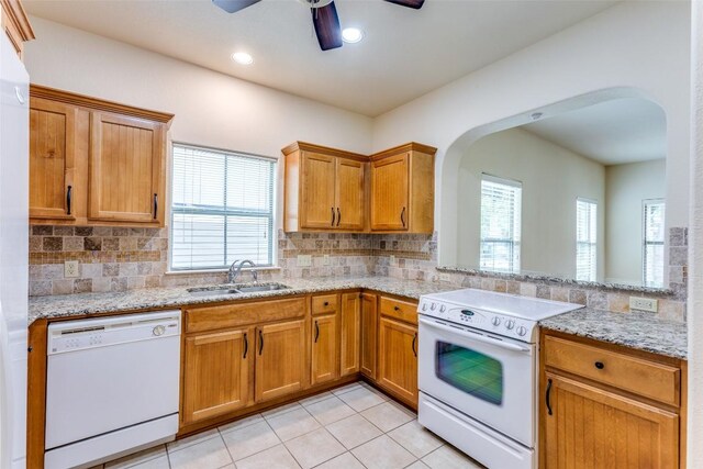 kitchen with white appliances, arched walkways, a wealth of natural light, and a sink