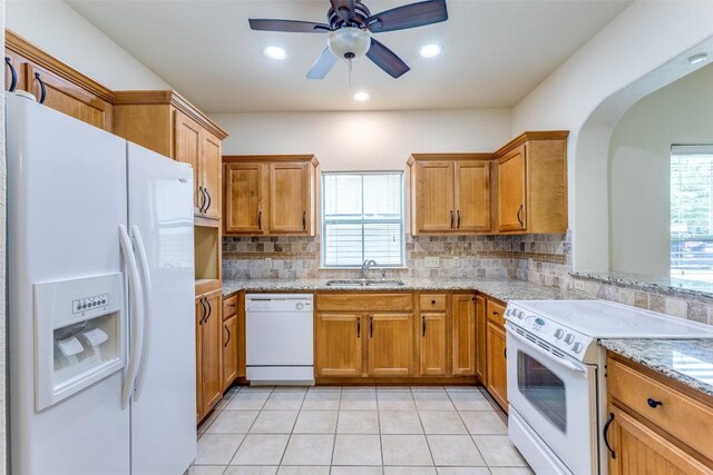 kitchen featuring white appliances, backsplash, plenty of natural light, and a sink