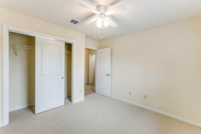 unfurnished bedroom featuring light colored carpet, a ceiling fan, baseboards, visible vents, and a closet