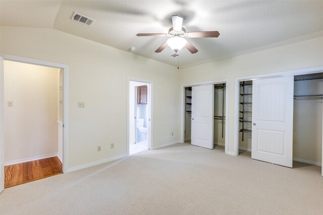 unfurnished bedroom with connected bathroom, ceiling fan, light carpet, multiple closets, and visible vents