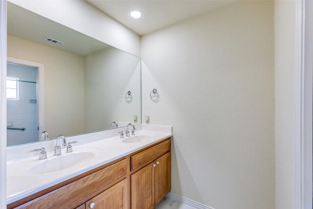 bathroom with a sink, baseboards, double vanity, and visible vents