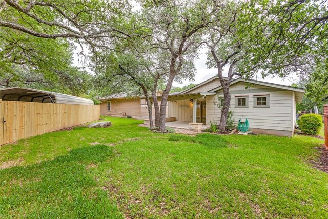back of house with a detached carport, a patio area, and a yard