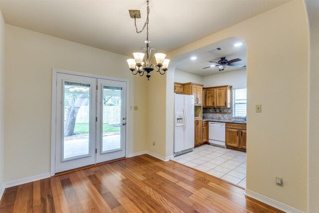 kitchen featuring brown cabinets, baseboards, ceiling fan with notable chandelier, light wood-style floors, and white appliances