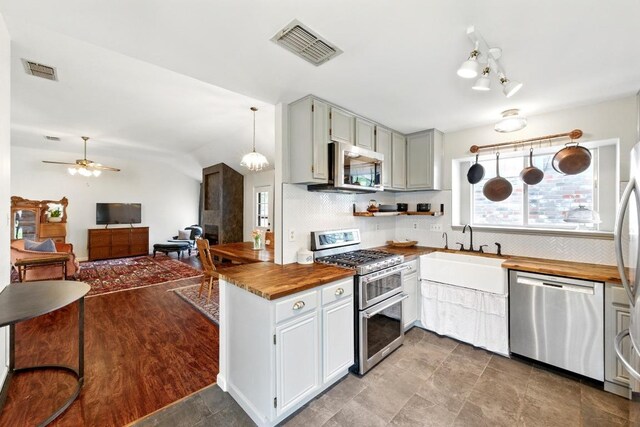 kitchen featuring stainless steel appliances, visible vents, butcher block counters, and tasteful backsplash