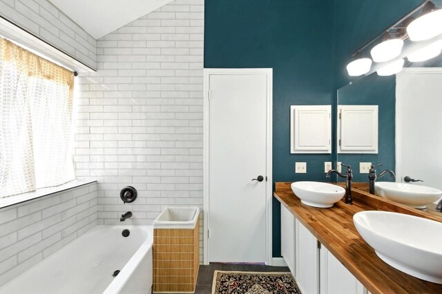 full bath with a sink, vaulted ceiling, and a garden tub