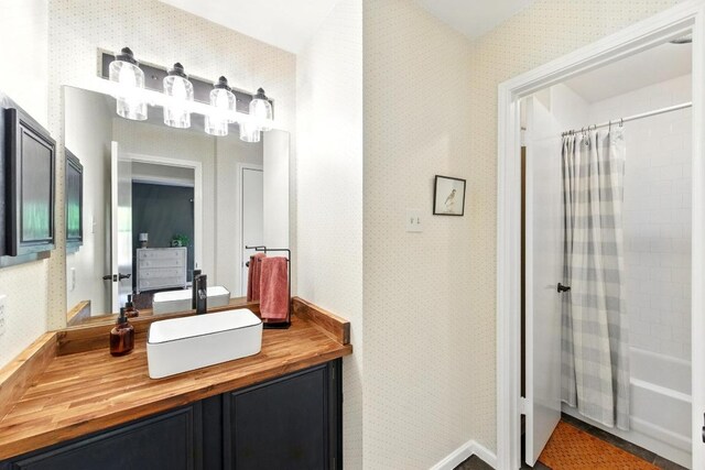 full bathroom with vanity, wallpapered walls, and shower / tub combo with curtain