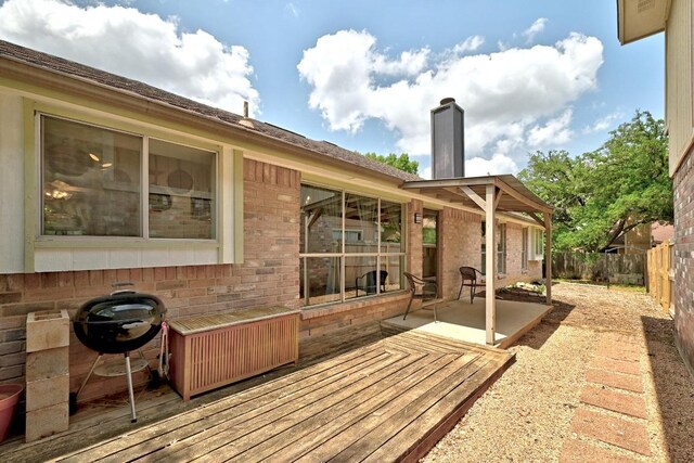 rear view of property with a fenced backyard, a chimney, a deck, and brick siding