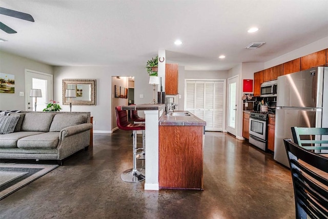 kitchen featuring open floor plan, finished concrete flooring, a breakfast bar, and stainless steel appliances
